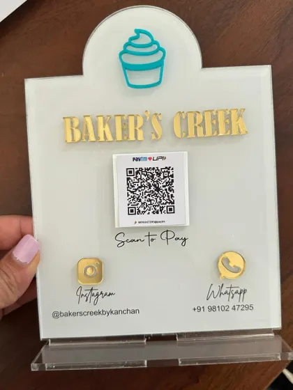 A clear, straight-on shot of the 'Baker's Creek' payment stand, highlighting the clean design and easy-to-read contact information.