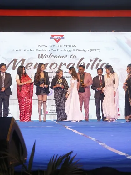 A student designer receives her award, surrounded by the esteemed jury and guests.