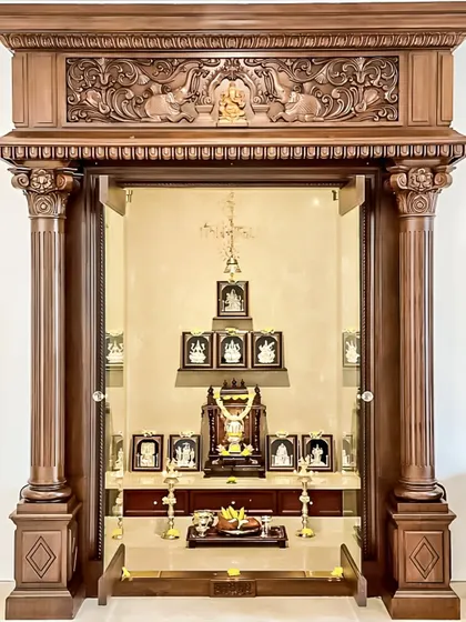 This magnificent pooja room entrance is a testament to classic temple architecture, designed to be the spiritual heart of the home. We incorporated robust, intricately carved wooden pillars and a traditional header featuring Gajalakshmi motifs, creating a grand and auspicious entryway.