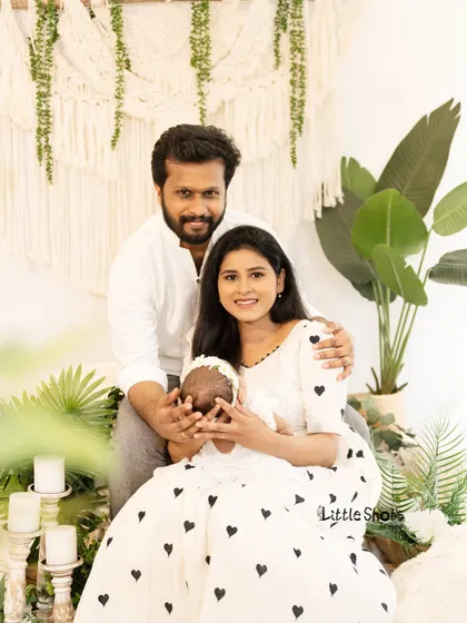 A beautiful family portrait capturing the love surrounding a new baby. The parents look proudly at the camera while the mother gently holds their newborn.