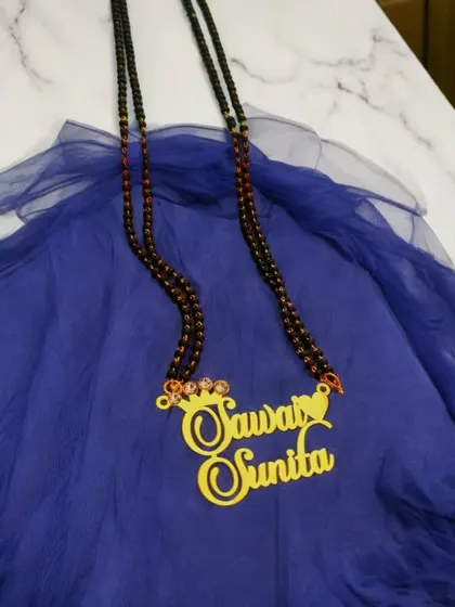 A customized double-name pendant with a crown detail, set on a long, double-stranded mangalsutra chain. This piece makes a bold and personal statement.