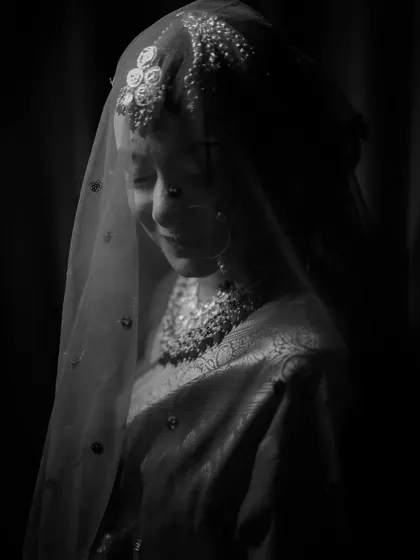 A soft and ethereal black and white portrait of a bride under her veil, capturing a moment of quiet grace.