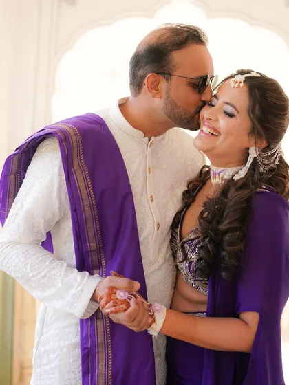 A sweet kiss on the cheek, this candid photo captures a tender moment between the couple during their vibrant Haldi ceremony.