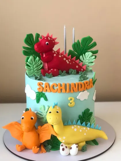 A side view of the three-dinosaur cake, showing the pterodactyl and stegosaurus figures.