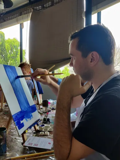 A painter working on a waterfall scene, with other artists in the background. The shared creative energy in our studio is one of our favorite things.