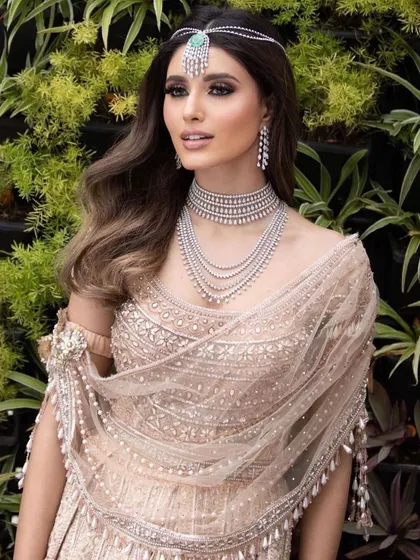 A modern take on reception glamour with soft, flowing hair and diamond jewelry. The makeup is clean and sophisticated, with a focus on a flawless base and a subtly defined eye.