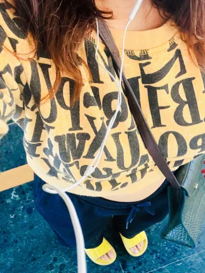 A top-down view of the graphic sweatshirt outfit, showing the full casual look with yellow slides.