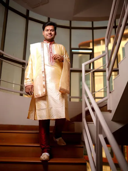 A full-length shot of the groom descending a modern staircase. This portrait captures his style and the anticipation of the wedding day.