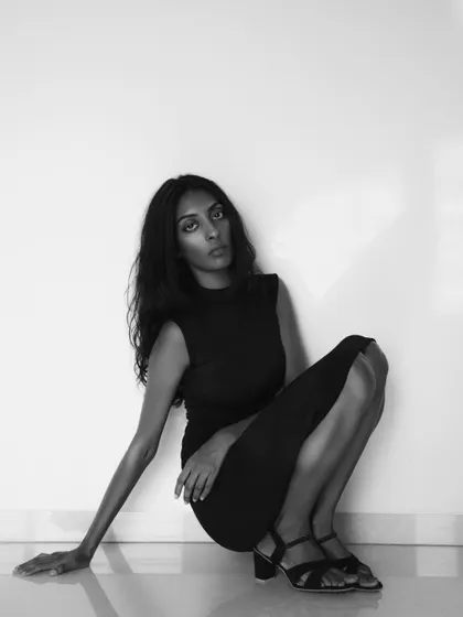 A full-length black and white portrait with a strong, graphic quality. The pose is both elegant and powerful.