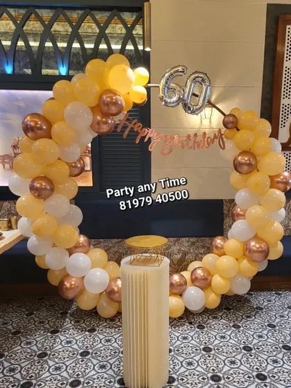 A simple balloon decoration in a restaurant, with a yellow, white, and rose gold circular arch.