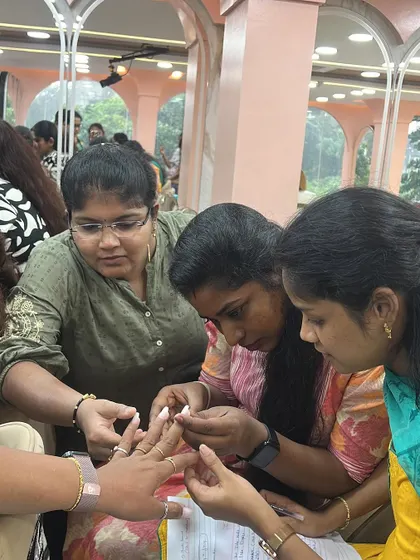 A close-up of students helping each other apply nail extensions.