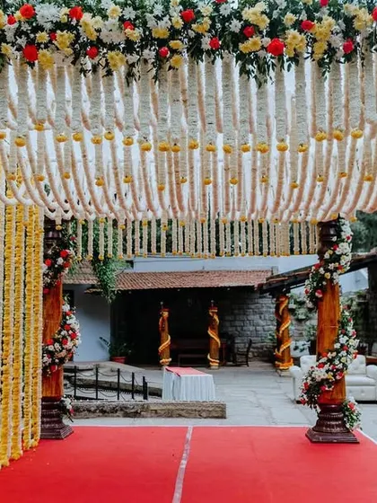 A grand entrance to a traditional wedding ceremony, with a path leading to a mandap decorated with tuberose and marigold garlands.