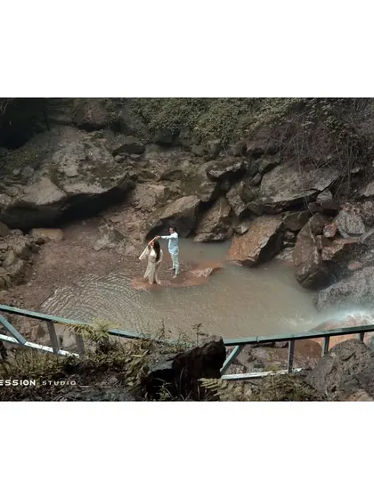 A wide shot capturing the couple dancing in a secluded water cove. This image highlights the beauty of the natural location, making them seem like the only two people in the world.