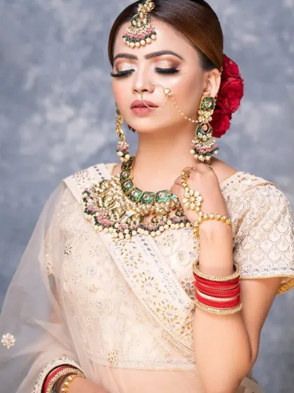 This look is all about modern elegance. The bride pairs an off-white outfit with a statement meenakari necklace featuring green and pink details.