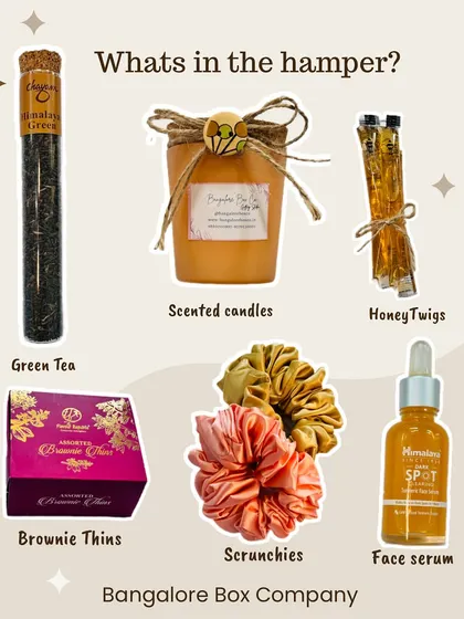 A flat lay of our special Mother's Day giveaway hamper. It includes green tea, a scented candle, honey twigs, brownie thins, scrunchies, and a face serum, a perfect pamper package.