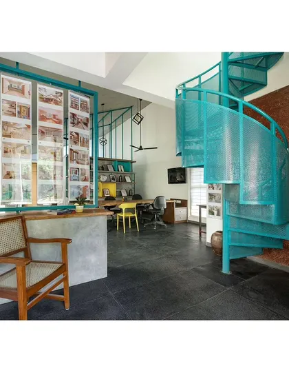This space was designed as a home office, featuring a perforated metal spiral staircase for access. The design is functional and space-efficient, with a large window providing ample light for the workspace.