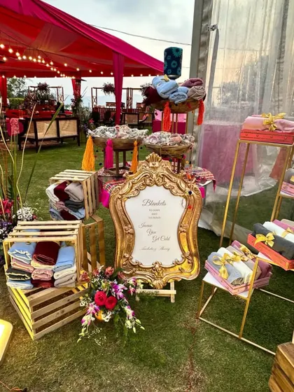 For a chilly evening event, we set up this thoughtful favor station with warm blankets. The elegant sign and organized display in crates and on stands make it both a practical and stylish addition to the decor.