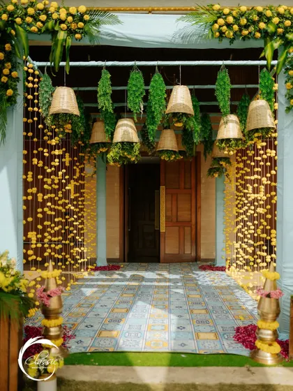 For a traditional Haldi or Mehendi, I created this charming entrance using strings of marigolds, hanging wicker baskets, and a patterned tile floor to give it a rustic and authentic desi feel.