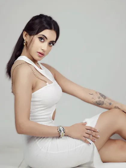 A seated portrait in a modern white dress. The pose is elegant and strong, and the clean background ensures all attention is on the model and her confident expression.