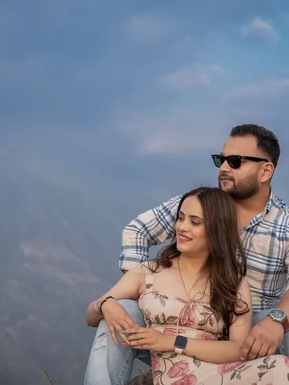 A quiet and intimate portrait of the couple sitting together, with the vastness of the mountains and sky behind them.