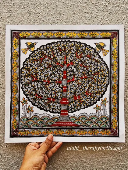 Holding the 'Tree of Life' painting against a textured wall. This helps visualize how the piece would look in a home setting.