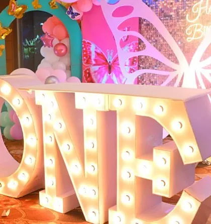 A close-up of the "ONE" marquee letter table, a popular centerpiece for first birthday celebrations. This is part of a larger butterfly-themed decoration.