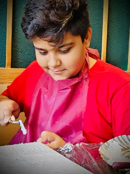 A young artist learning to use a palette knife to apply texture paste. Our workshops are designed to be accessible and fun for all ages.