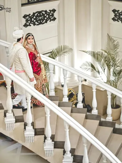 An elegant portrait of the couple on a grand white staircase. We utilize the architecture of your venue to create stunning, magazine-worthy wedding photos.