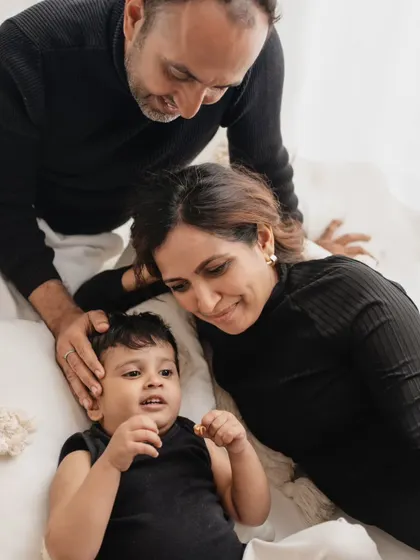 A quiet, intimate moment during a family session. The parents look down lovingly at their son, creating a feeling of warmth and protection.