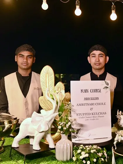 Two of our team members proudly standing by their main course station, ready to serve Amritsari Chole and Stuffed Kulchas.