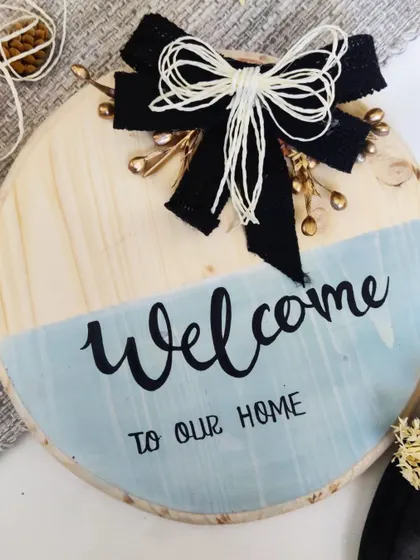 This "Welcome to our Home" sign features a stylish black bow and gold accents, offering a more modern and chic take on our classic welcome boards.
