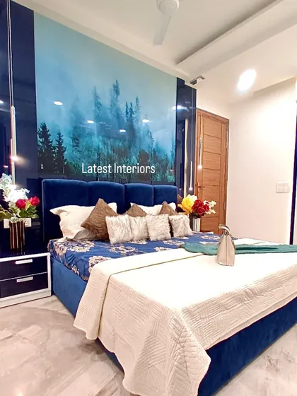 A vibrant blue bedroom in Janakpuri, featuring a stunning custom headboard with a serene forest landscape. This design shows how a bold color and personalized art can create a unique and luxurious sanctuary.