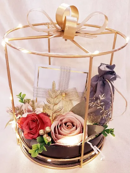 Make any occasion extraordinary with our elegant hampers. This metal cage hamper is lit with fairy lights and contains beautifully wrapped gifts, creating a magical unboxing experience.