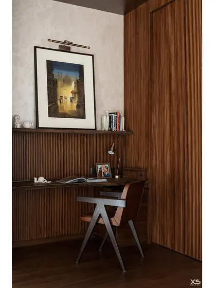 The study nook is a quiet corner for focus, featuring a sleek wooden desk and a classic Pierre Jeanneret chair.
