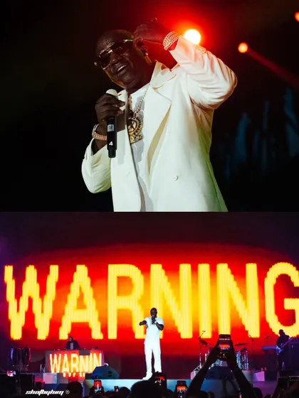 A split-screen view of Akon's concert, showing him performing on a grand scale with "WARNING" displayed on the screen behind him.