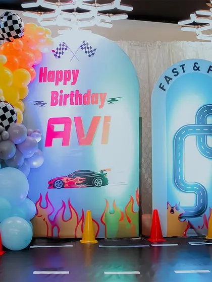 The complete Hot Wheels "Fast & Five" backdrop, featuring a custom-printed race track, flame details, and checkered flag balloons. The light-up number '5' adds a dynamic touch to the setup.