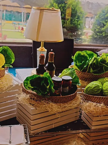 A fresh and green setup for our salad bar at an outdoor event. We use whole heads of lettuce and fresh vegetables as part of the decor, emphasizing the farm-to-table quality of our ingredients.