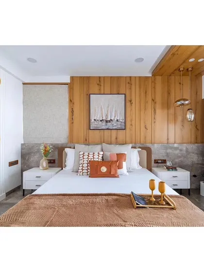 A close-up view of our bedroom styling, featuring a wood-paneled accent wall and modern white nightstands. We use decorative pillows and accessories to add pops of color and personality.