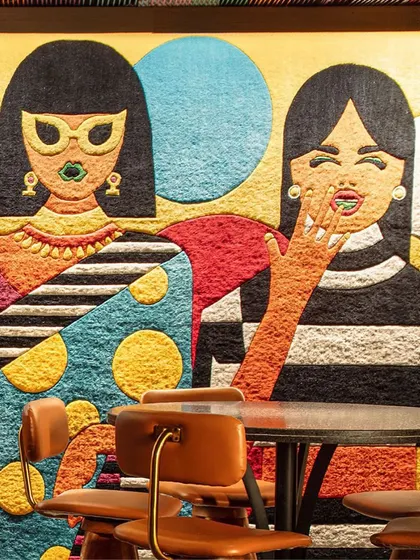 A close-up of the bespoke wall carpet at Khi Khi, a custom creation by The Carpet Cellar. The design features whimsical, giggling motifs and a curated explosion of colors that perfectly captures the bar's playful spirit.