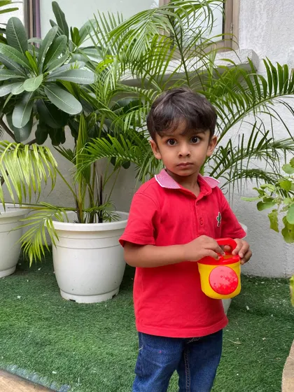 This little boy is focused on his task of watering the plants. We believe that connecting with nature at a young age is crucial for holistic development.