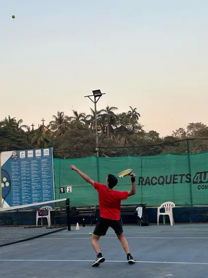 A player unleashes a powerful serve during an evening session. Our training covers all aspects of the game, day or night.