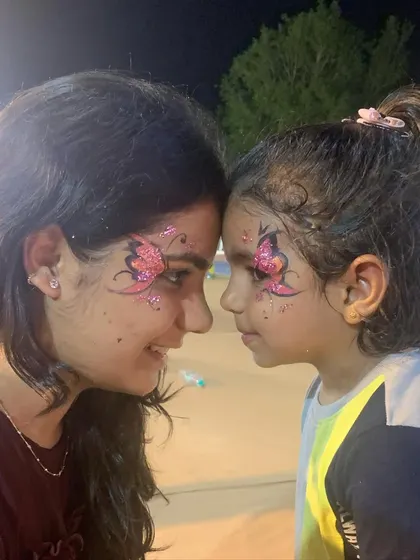 A sweet moment between two friends or sisters showing off their matching pink butterfly face paint.