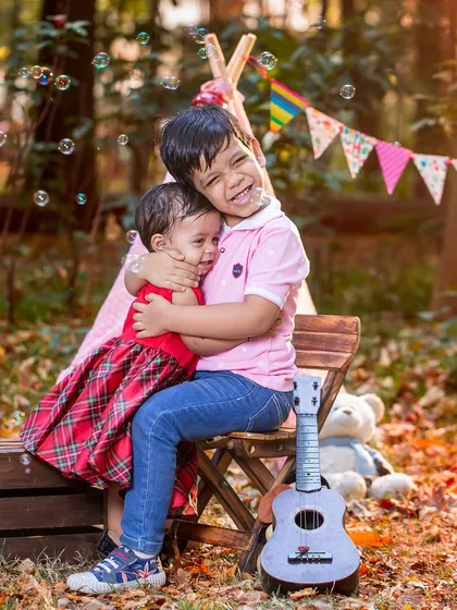 A big brother gives his little sister a tight hug in a cozy outdoor camp setting. This photo is overflowing with sibling love and pure, unscripted joy.