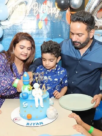 The cake cutting moment at a space-themed birthday party, featuring an astronaut and planet-topped cake.