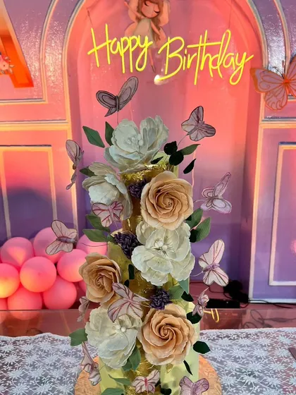 A close-up of the stunning butterfly-themed cake, adorned with intricate, lifelike sugar flowers and dozens of delicate butterflies that appear to be fluttering up the tiers.