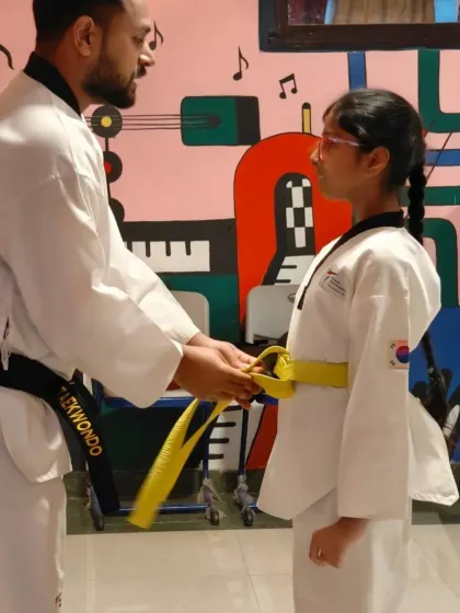 A proud moment for every student: earning their next belt. We focus on personal attention and guidance, helping each student, like this young girl receiving her yellow belt, progress with confidence.