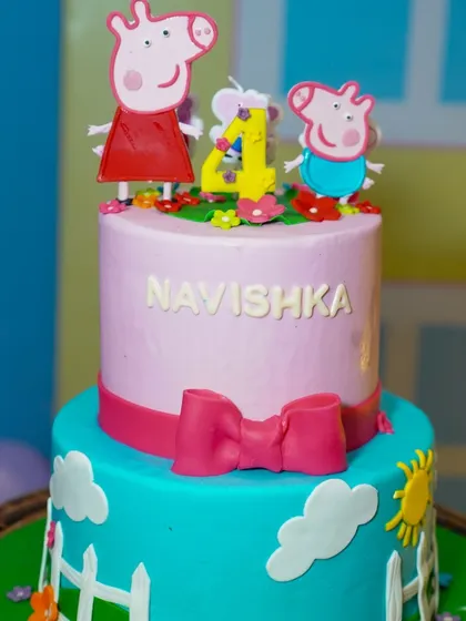 A close-up of the adorable two-tiered Peppa Pig cake, complete with character toppers and a cheerful design.