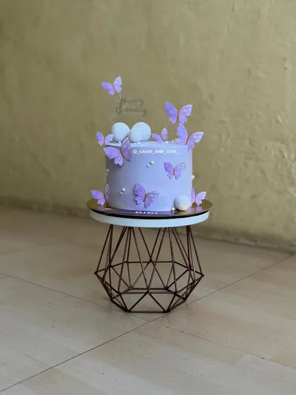 A soft purple cake decorated with fluttering butterflies and pearl-like details.
