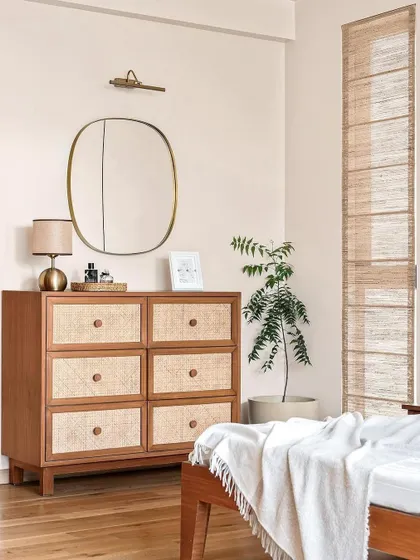 This image from a magazine feature shows the master bedroom, where a rattan-front chest of drawers and banana fiber blinds create a cohesive, earthy look.