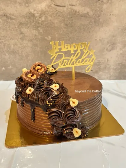 A delicious chocolate hazelnut drip cake with a cascade of piped chocolate cream and toasted hazelnuts.